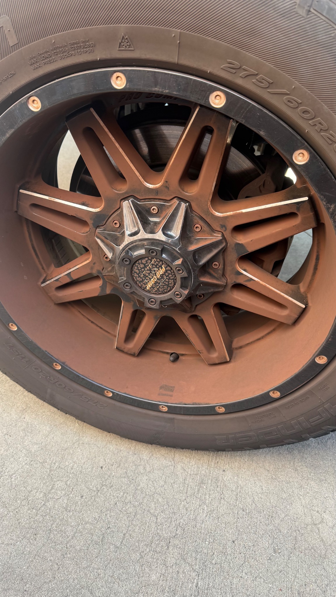 Wheel and tire covered in brown dirt before exterior cleaning