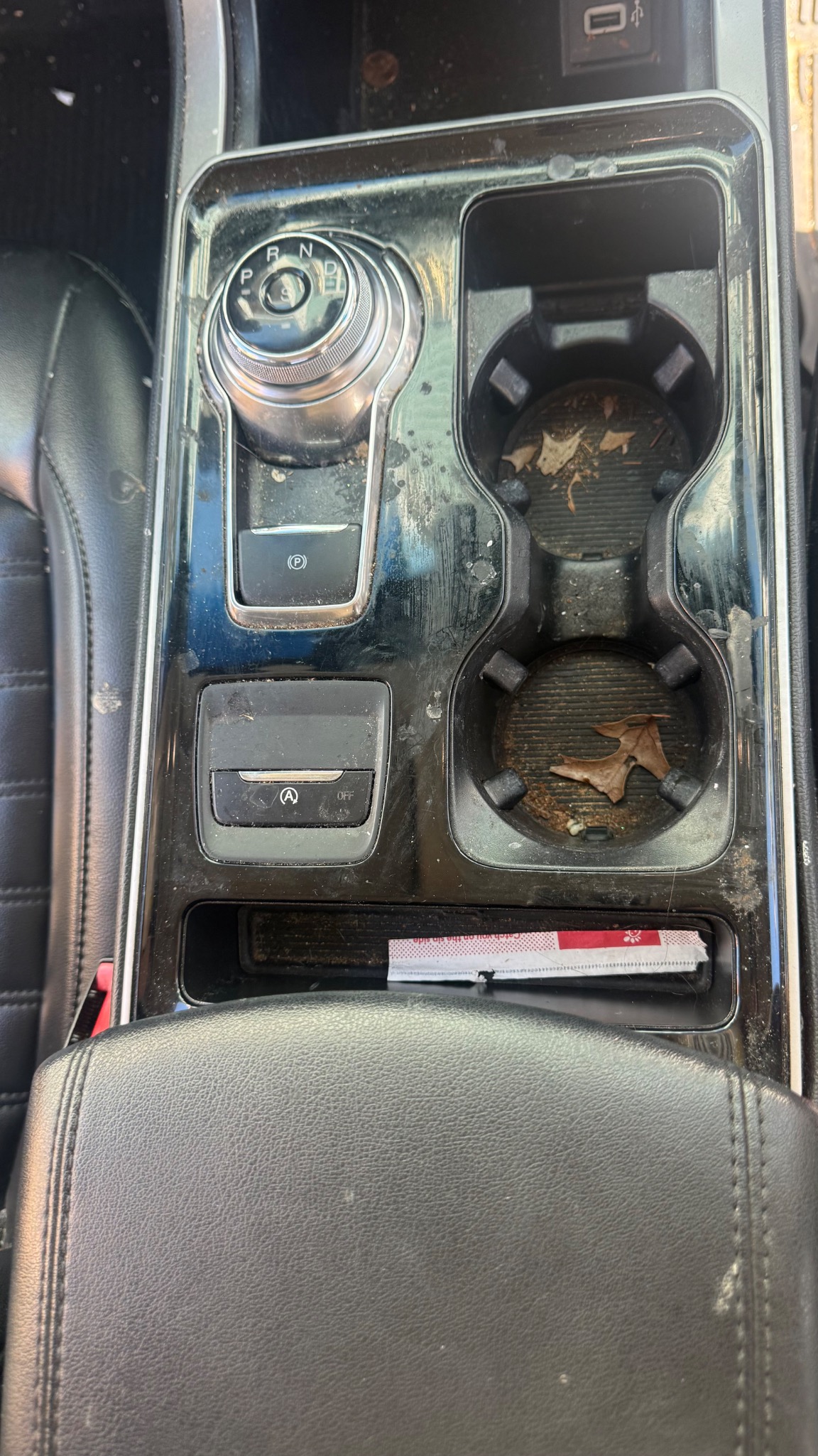 Center console and cup holders with dirt and debris before interior detailing